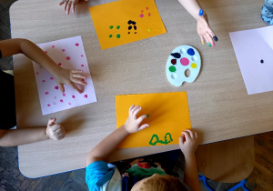 Dzieci malują zakropkowane obrazy palcami zamoczonymi w farbie